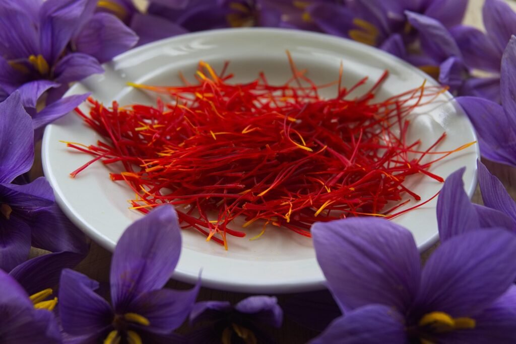 A saffron-infused dish presented alongside dried saffron threads and a fresh saffron flower, visually highlighting the quality, color, and aroma of premium saffron. Perfect for illustrating a guide on how to choose high-quality saffron for cooking.