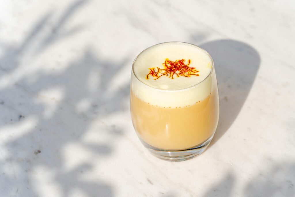 Cup of warm saffron milk with visible saffron strands, known for health benefits like better sleep, glowing skin, and hormone balance.